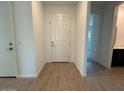 A home's entryway with wood look tile, white walls, and a white front door at 15773 W Beryl Ave, Waddell, AZ 85355