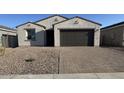 A single-story home with a two-car garage, gravel yard and a paved driveway at 15773 W Beryl Ave, Waddell, AZ 85355