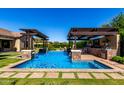 Resort-style pool area with pergola, outdoor kitchen, and beautiful water feature at 17673 E Bronco Dr, Queen Creek, AZ 85142