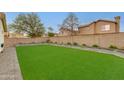 Expansive backyard with artificial turf, mature landscaping, and a concrete block fence at 21940 N 69Th Dr, Glendale, AZ 85310