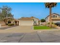 Charming single-story home featuring a tiled roof, attached garage, manicured lawn, and mature trees at 21940 N 69Th Dr, Glendale, AZ 85310