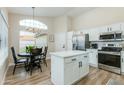 Modern kitchen featuring white cabinets, stainless steel appliances, island, breakfast nook, and large window at 21940 N 69Th Dr, Glendale, AZ 85310