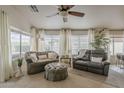 Cozy living room with comfortable seating, ceiling fan, and natural light from large windows at 2394 E Santiago Trl, Casa Grande, AZ 85194