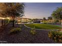 Expansive backyard featuring a stunning pool with rock accents, lush green lawn, mature trees, and beautiful landscaping at 4547 S Banning Dr, Gilbert, AZ 85297