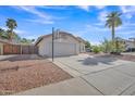 View of single-story home with large driveway, desert landscaping, basketball hoop and tile roof at 515 W Smoke Tree Rd, Gilbert, AZ 85233