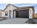 Stylish exterior of home featuring a dark two car garage and desert rock landscaping at 7657 W Minton St, Laveen, AZ 85339