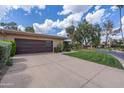 Home exterior featuring a modern garage door, desert landscaping, and well-kept front lawn at 7746 E Bisbee Rd, Scottsdale, AZ 85258