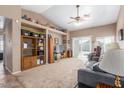 Spacious living room with neutral carpet, vaulted ceilings, a ceiling fan, and sliding doors to the backyard at 15351 W Port Royale Ln, Surprise, AZ 85379