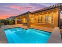 Twilight view of a stunning backyard with pool, covered patio, and lighting at 175 E Santa Lucia Ln, Queen Creek, AZ 85140