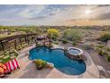 Aerial view of a stunning pool area with spa, pergola, outdoor seating, and lush landscaping surrounded by desert beauty at 18438 N 96Th Way, Scottsdale, AZ 85255