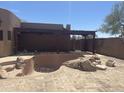 A uniquely designed, unfinished backyard pool with a stone-laid patio, under a rustic wooden pergola at 20042 W Colter St, Litchfield Park, AZ 85340
