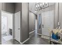 Welcoming home entryway showcasing the front door, modern lighting fixture, and sleek wood floors at 26743 N 65Th Dr, Phoenix, AZ 85083
