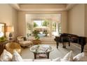 Bright living room with a large picture window view of the backyard pool and a grand piano at 6243 E Camelback Rd, Scottsdale, AZ 85251