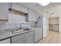 Bright kitchen with stainless sink, gray cabinets, white subway tile backsplash and white appliances at 7765 W Glenn Dr, Glendale, AZ 85303
