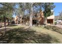 Back exterior view of multi-story homes with a lush green lawn and mature shade trees at 1425 E Desert Cove Ave # 35, Phoenix, AZ 85020