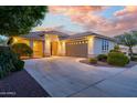 Beautiful single-story home featuring desert landscaping, three car garage and a neutral color palette at dusk at 15796 W Shaw Butte Dr, Surprise, AZ 85379