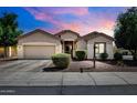 The exterior of the home, featuring a well-maintained yard and neutral-colored facade under a beautiful dusk sky at 16861 W Ironwood St, Surprise, AZ 85388