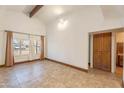 Bright living room features neutral paint, tile flooring, and vaulted ceilings with exposed beams at 2445 W Yuma St, Phoenix, AZ 85009