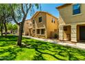 View of a two-story townhome with desert landscaping, lawn, and shady mature trees at 3485 S Seneca Way, Gilbert, AZ 85297