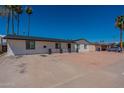 Attractive white brick home with a modern black roof, ample parking, and mature trees under a clear blue sky at 3802 W Mission Ln, Phoenix, AZ 85051