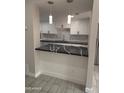 Kitchen with white cabinets, black countertops, stainless steel sink, and subway tile backsplash, open to living space at 4043 W Palomino Rd, Phoenix, AZ 85019