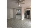 Open-concept living area with tile flooring, ceiling fan, and a passthrough to the updated kitchen with stainless refrigerator at 4043 W Palomino Rd, Phoenix, AZ 85019