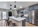 Modern kitchen with stainless steel appliances, sleek countertops, an island with seating, and stylish blue cabinets at 5228 W Aster Dr, Glendale, AZ 85304