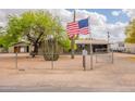 Home exterior featuring mature landscaping, a fence and a welcoming American flag at 10437 E Boulder Dr, Apache Junction, AZ 85120