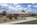Charming single-story home featuring a well-manicured front yard, a tile roof, and a three-car garage at 11003 E Kiva Ave, Mesa, AZ 85209
