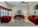 Spacious living room with high ceilings, shuttered windows and comfortable red sofas and armchairs at 14334 W Shawnee Trl, Surprise, AZ 85374