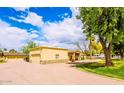 Single-story home with spacious driveway and garage, accented by a lush green lawn, mature trees and stone accents at 1438 E Mesquite St, Gilbert, AZ 85296