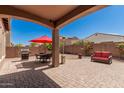 Inviting backyard with covered patio, pavers, seating, BBQ grill, and a well-maintained landscape with a red umbrella at 3269 E Ironside Ln, Gilbert, AZ 85298