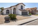 Charming two-story home with an arched entry, tile roof, desert landscaping, and a two car garage at 7869 W Market St, Glendale, AZ 85303