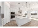 Open kitchen with white cabinets, modern appliances, and a spacious island with pendant lighting at 11660 W Luxton Ln, Avondale, AZ 85323