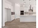 Bright kitchen with white cabinets, stainless steel appliances, and wood-style tile flooring at 11660 W Luxton Ln, Avondale, AZ 85323