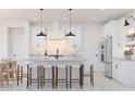 Modern white kitchen with a center island, stainless steel appliances, and stylish pendant lighting at 20309 W Roma Ave, Buckeye, AZ 85396