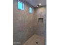 Walk-in shower with neutral-toned tile, a built-in niche, and natural light from the window at 24170 N 172Nd Ave, Surprise, AZ 85387