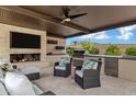 A stylish outdoor living space features a fireplace, TV, built-in grill, and comfortable seating under a covered patio at 30129 N 52Nd Pl, Cave Creek, AZ 85331