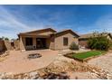 Home's backyard featuring brick patio, small lawn, and desert landscaping at 42311 W Bunker Dr, Maricopa, AZ 85138