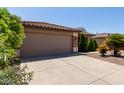 Picture of a home's two-car garage and landscaped front yard, including desert foliage at 42311 W Bunker Dr, Maricopa, AZ 85138