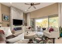 Bright living room featuring a stacked stone accent wall with fireplace and backyard patio views at 6094 E Evening Glow Dr, Scottsdale, AZ 85266