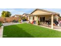 Expansive backyard showcasing lush artificial turf, play equipment, outdoor seating and mature landscaping at 12425 W Willow Ave, El Mirage, AZ 85335