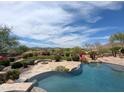 A backyard pool features a stone patio, lush landscaping, and mountain views in this desert home at 12711 N 117Th St, Scottsdale, AZ 85259