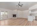 Open-concept living room with fireplace, light wood floors, and a ceiling fan blending into the updated kitchen at 16402 N 31St St # 232, Phoenix, AZ 85032