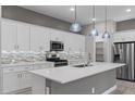 Modern kitchen featuring sleek white cabinetry, stainless steel appliances, pendant lighting, and a spacious center island at 16945 W Vernon Ave, Goodyear, AZ 85395
