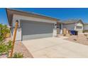 View of a two-car garage and driveway with desert rock landscaping at 16996 W Fetlock Trl, Surprise, AZ 85387