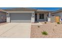 Charming single-story home featuring a gray garage door and desert landscaping at 16996 W Fetlock Trl, Surprise, AZ 85387