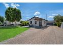 Charming single-story home features a well-manicured lawn, brick driveway and inviting porch with wooden pillars at 2316 N Mitchell St, Phoenix, AZ 85006