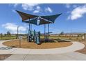 Community playground area with a modern shade structure, play equipment, and safe ground cover for children at 24649 W Jessica Ln, Buckeye, AZ 85326