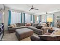 Spacious living room featuring a large sectional couch, ceiling fans, and natural light from several windows at 26049 W Matthew Dr, Buckeye, AZ 85396